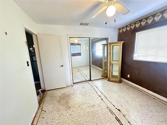 unfurnished bedroom with a closet, multiple windows, and ceiling fan