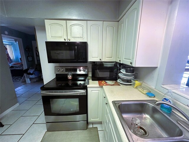 kitchen with light tile patterned floors, sink, electric range, and white cabinets