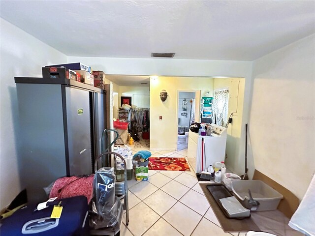 kitchen featuring washer / clothes dryer, stainless steel fridge, and light tile patterned floors