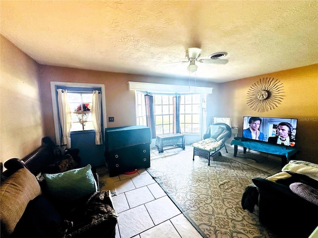 tiled living room featuring ceiling fan, a textured ceiling, and plenty of natural light