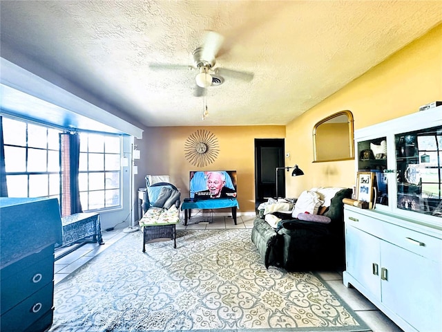 living room with a textured ceiling, light tile patterned floors, and ceiling fan