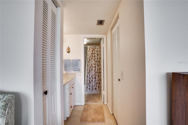 hall with a textured ceiling and visible vents