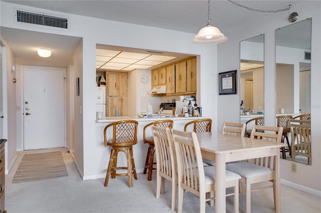 carpeted dining area with a textured ceiling