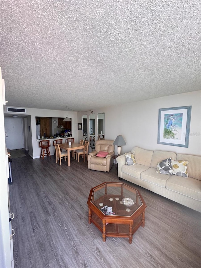 living room featuring dark wood-style floors, visible vents, and a textured ceiling