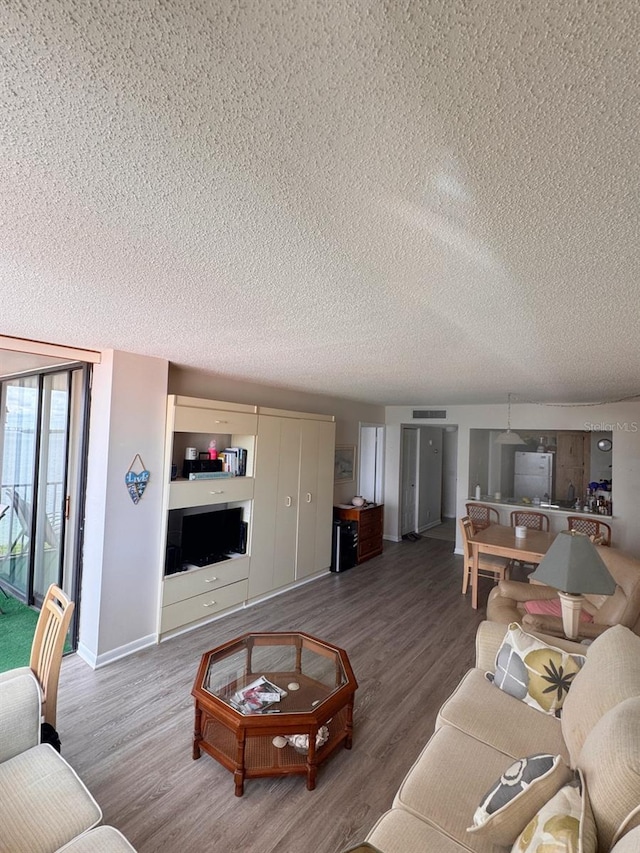 living room with visible vents, a textured ceiling, baseboards, and wood finished floors