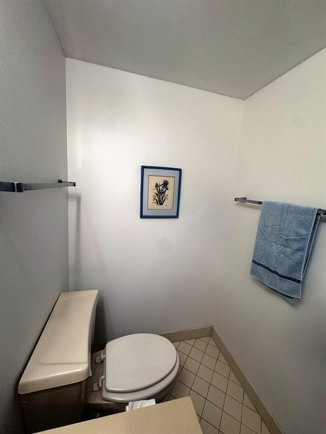 half bathroom featuring toilet, baseboards, and tile patterned floors