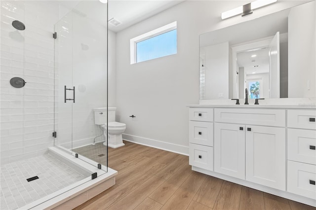 bathroom with toilet, vanity, a shower with shower door, and wood-type flooring