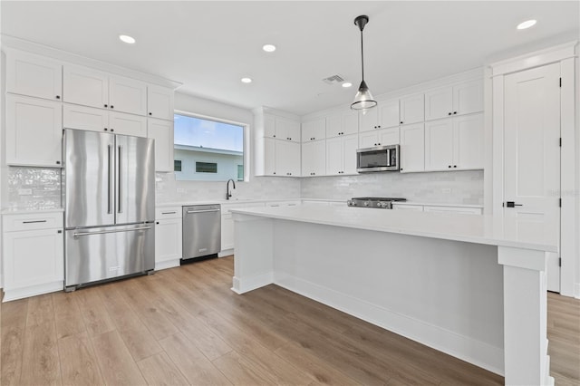 kitchen with sink, appliances with stainless steel finishes, white cabinets, and hanging light fixtures