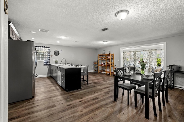 dining area featuring a textured ceiling, dark hardwood / wood-style flooring, and sink