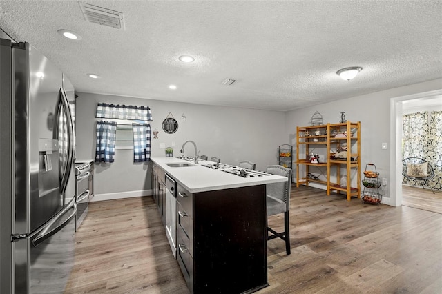 kitchen with appliances with stainless steel finishes, hardwood / wood-style floors, a textured ceiling, and kitchen peninsula