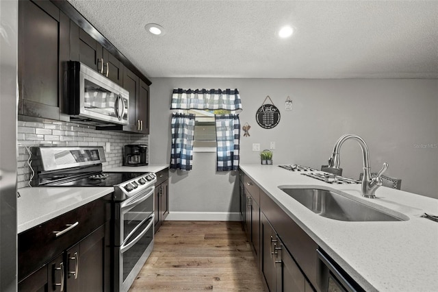 kitchen featuring backsplash, stainless steel appliances, light hardwood / wood-style floors, sink, and a textured ceiling