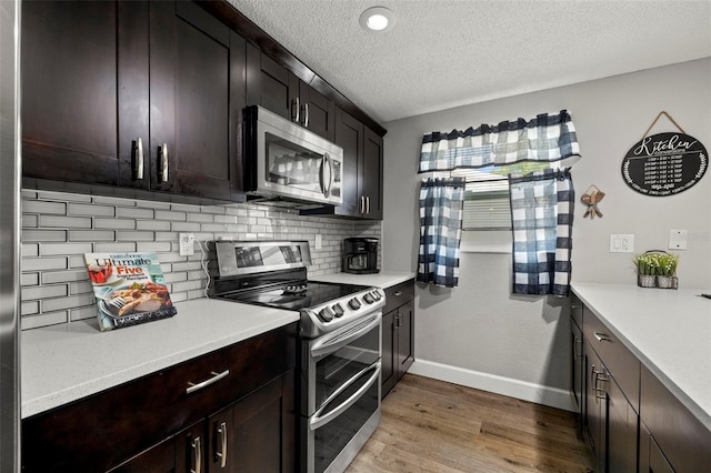 kitchen featuring appliances with stainless steel finishes, backsplash, dark brown cabinetry, a textured ceiling, and wood-type flooring