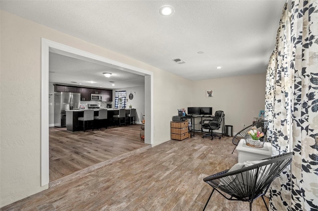 office with light wood-type flooring and a textured ceiling