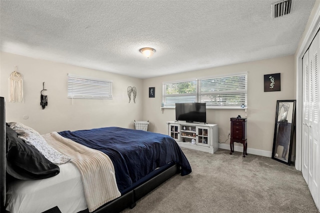 carpeted bedroom with a closet and a textured ceiling