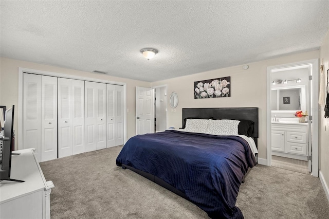 carpeted bedroom with a textured ceiling and ensuite bath