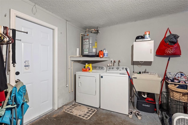 clothes washing area featuring a textured ceiling, electric water heater, sink, and separate washer and dryer