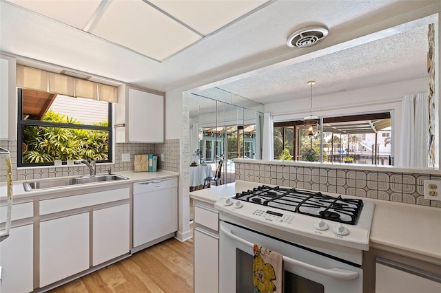 kitchen featuring tasteful backsplash, white appliances, sink, white cabinetry, and plenty of natural light