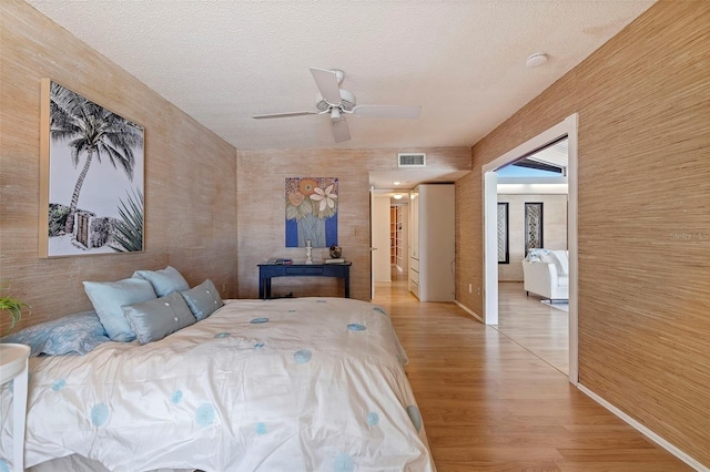 bedroom with ceiling fan, wood-type flooring, and a textured ceiling