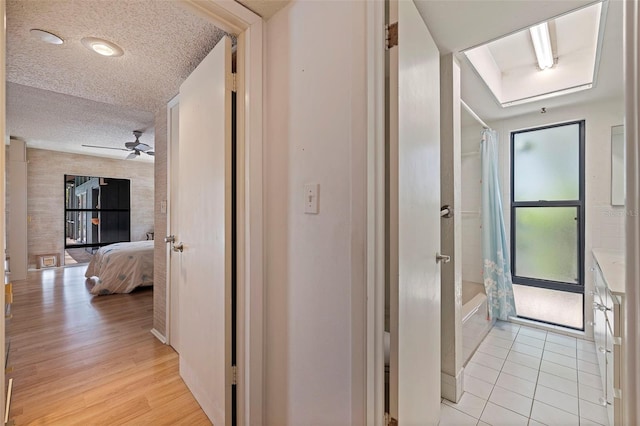 hall with a textured ceiling and light wood-type flooring