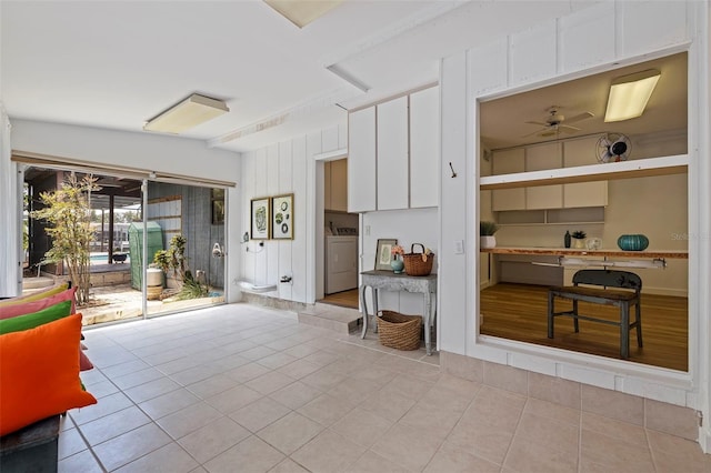 interior space featuring white cabinets, ceiling fan, washer / dryer, and light tile patterned floors