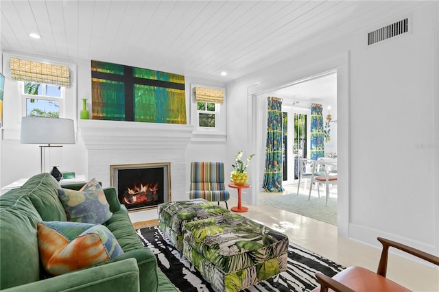 living room with a fireplace, wooden ceiling, and concrete flooring