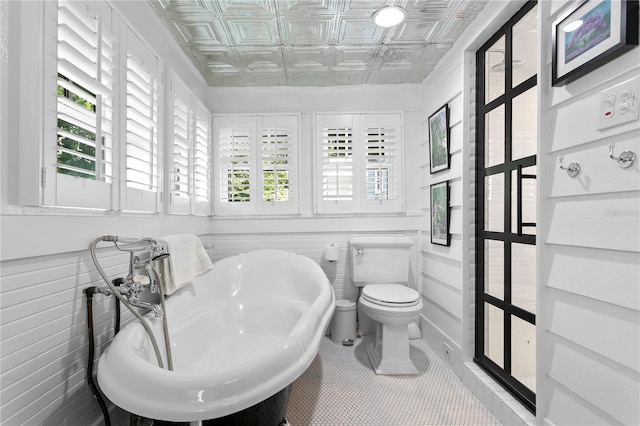 bathroom featuring tile patterned flooring, tile walls, toilet, and sink