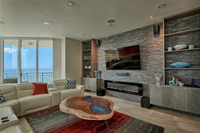 living room with light tile patterned floors, a wall of windows, a stone fireplace, and built in features