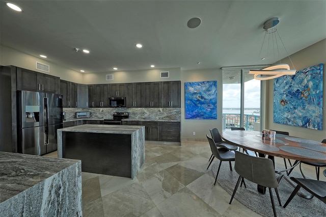 kitchen featuring appliances with stainless steel finishes, dark brown cabinetry, hanging light fixtures, and decorative backsplash