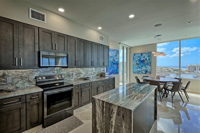 kitchen with appliances with stainless steel finishes, backsplash, light stone counters, and light tile patterned floors