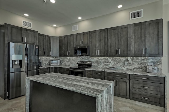 kitchen with light stone counters, appliances with stainless steel finishes, dark brown cabinets, light tile patterned floors, and backsplash