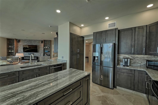 kitchen featuring light tile patterned floors, sink, dishwashing machine, light stone counters, and stainless steel fridge