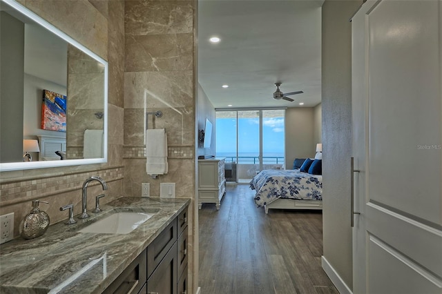 bathroom with ceiling fan, tile walls, hardwood / wood-style flooring, a shower, and vanity