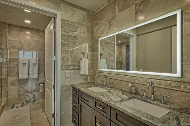 bathroom with tile walls, double sink vanity, tile patterned floors, and tasteful backsplash