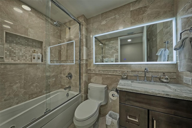 full bathroom featuring toilet, combined bath / shower with glass door, backsplash, tile walls, and vanity