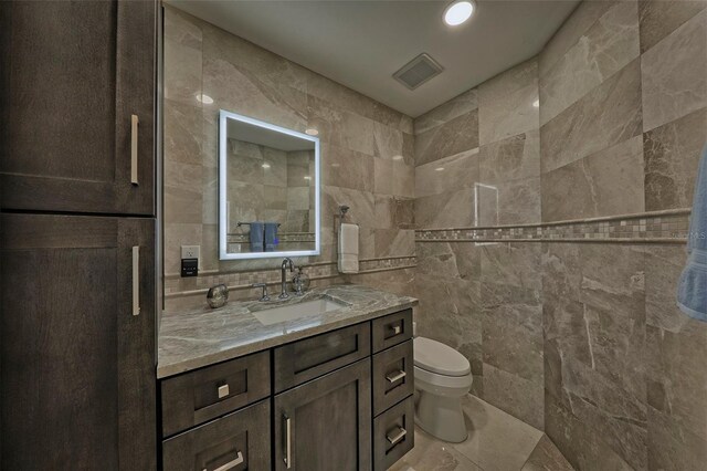 bathroom featuring tile patterned floors, tile walls, vanity, and toilet