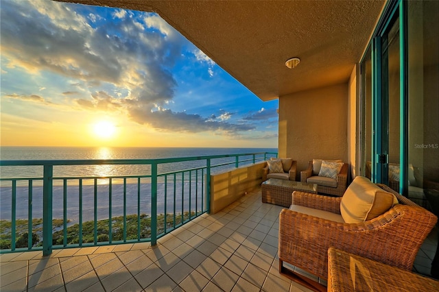 balcony at dusk featuring an outdoor hangout area and a water view