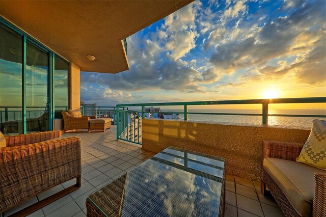 balcony at dusk with an outdoor hangout area and a water view