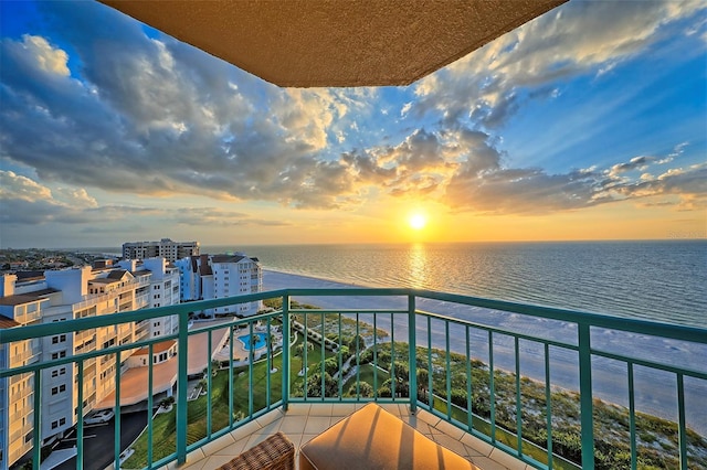 balcony at dusk featuring a water view