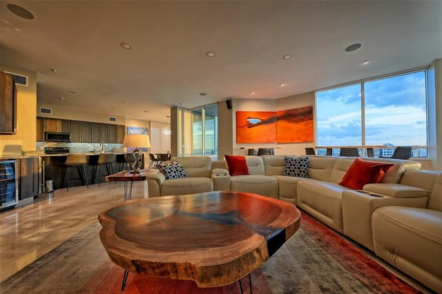 living room featuring tile patterned floors, a wall of windows, a healthy amount of sunlight, and beverage cooler