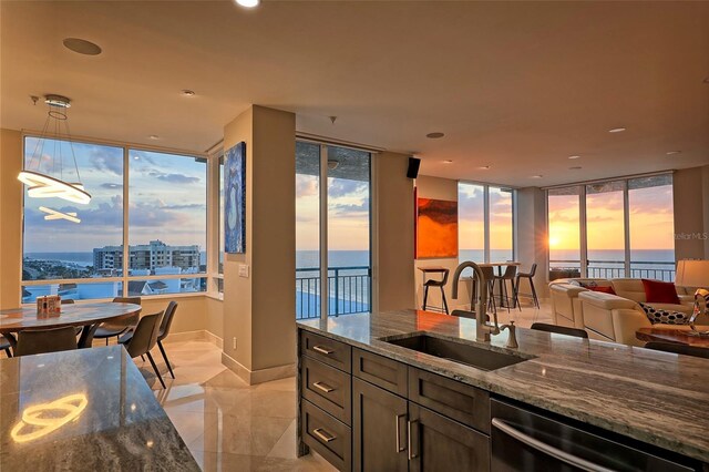 kitchen with sink, dishwasher, a water view, and dark stone counters