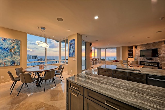 interior space with pendant lighting, light stone countertops, light tile patterned floors, sink, and dark brown cabinetry