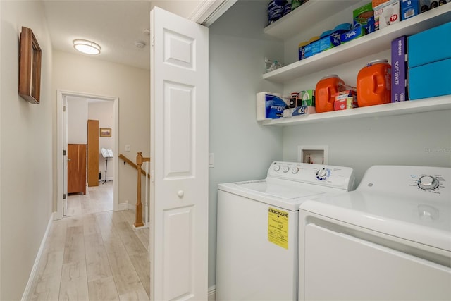 clothes washing area with washing machine and dryer and light hardwood / wood-style flooring