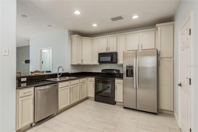 kitchen with cream cabinets, sink, dark stone counters, and black appliances