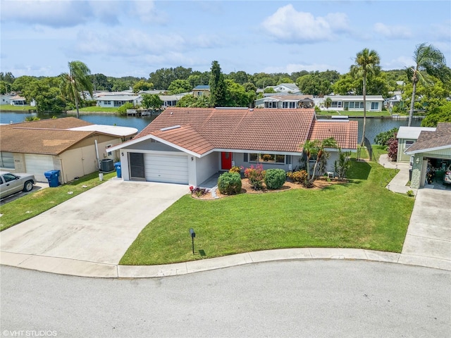 view of front of house featuring a front yard, driveway, an attached garage, a water view, and a tile roof