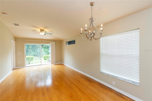 empty room with ceiling fan with notable chandelier and light hardwood / wood-style floors