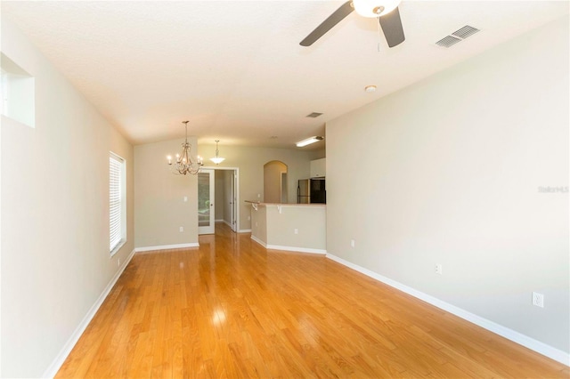 spare room with ceiling fan with notable chandelier and light hardwood / wood-style flooring