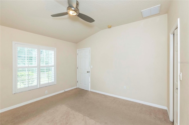 spare room featuring lofted ceiling, ceiling fan, light colored carpet, and a textured ceiling