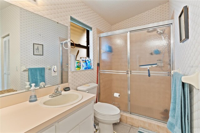 bathroom with a shower with door, vanity, toilet, and tile patterned floors