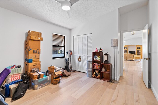 miscellaneous room with vaulted ceiling, a textured ceiling, light hardwood / wood-style flooring, and ceiling fan