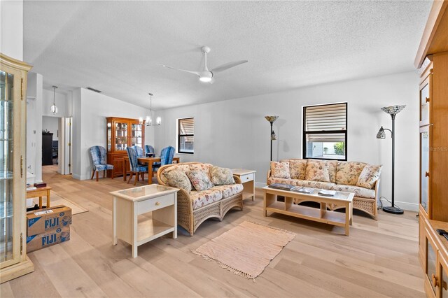 living room featuring ceiling fan with notable chandelier, light hardwood / wood-style floors, and a healthy amount of sunlight